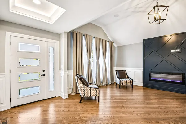 an empty room with wooden floor lounge chair and windows