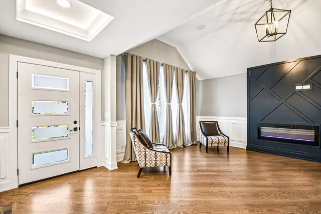 an empty room with wooden floor lounge chair and windows