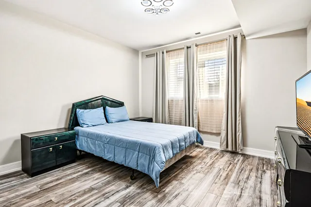 a bedroom with a bed and a flat tv screen on a dresser