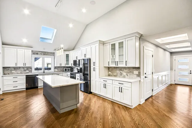 a large kitchen with stainless steel appliances kitchen island a large counter top and a wooden floors