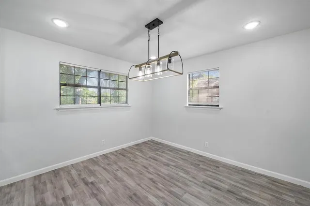 an empty room with wooden floor windows and ceiling fan