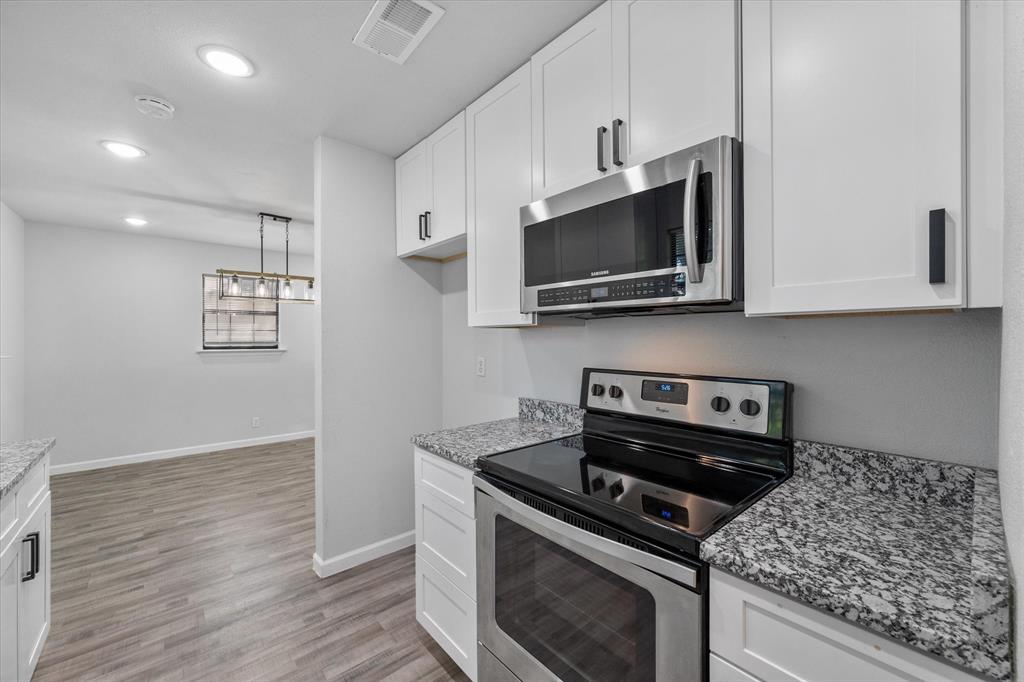1312 East Collin Street Corsicana, TX 75110 - Photo 15 of 24 a kitchen with stainless steel appliances granite countertop a stove a microwave and cabinets
