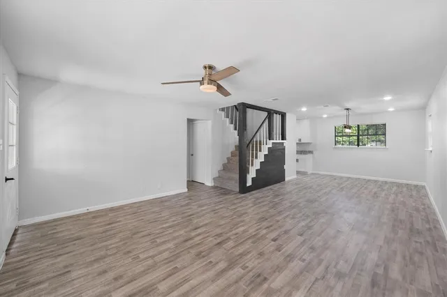 a view of empty room with wooden floor and ceiling fan