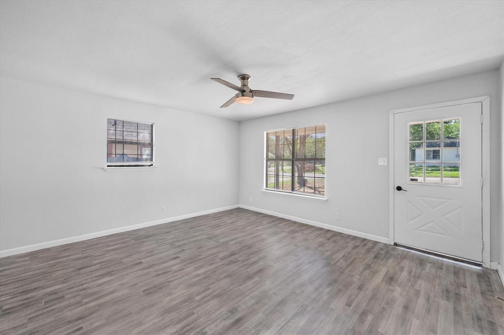 1312 East Collin Street Corsicana, TX 75110 - Photo 9 of 24 an empty room with wooden floor ceiling fan and windows