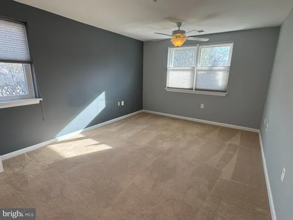 an empty room with windows and fan