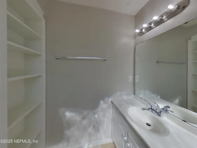 a bathroom with a sink vanity and shower