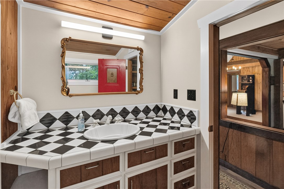 130 Maggie Rufus Lane Westminster, SC 29693 - Photo 17 of 50 Bold black and white tiled vanity with a charming gold-framed mirror and rustic wood ceiling.
