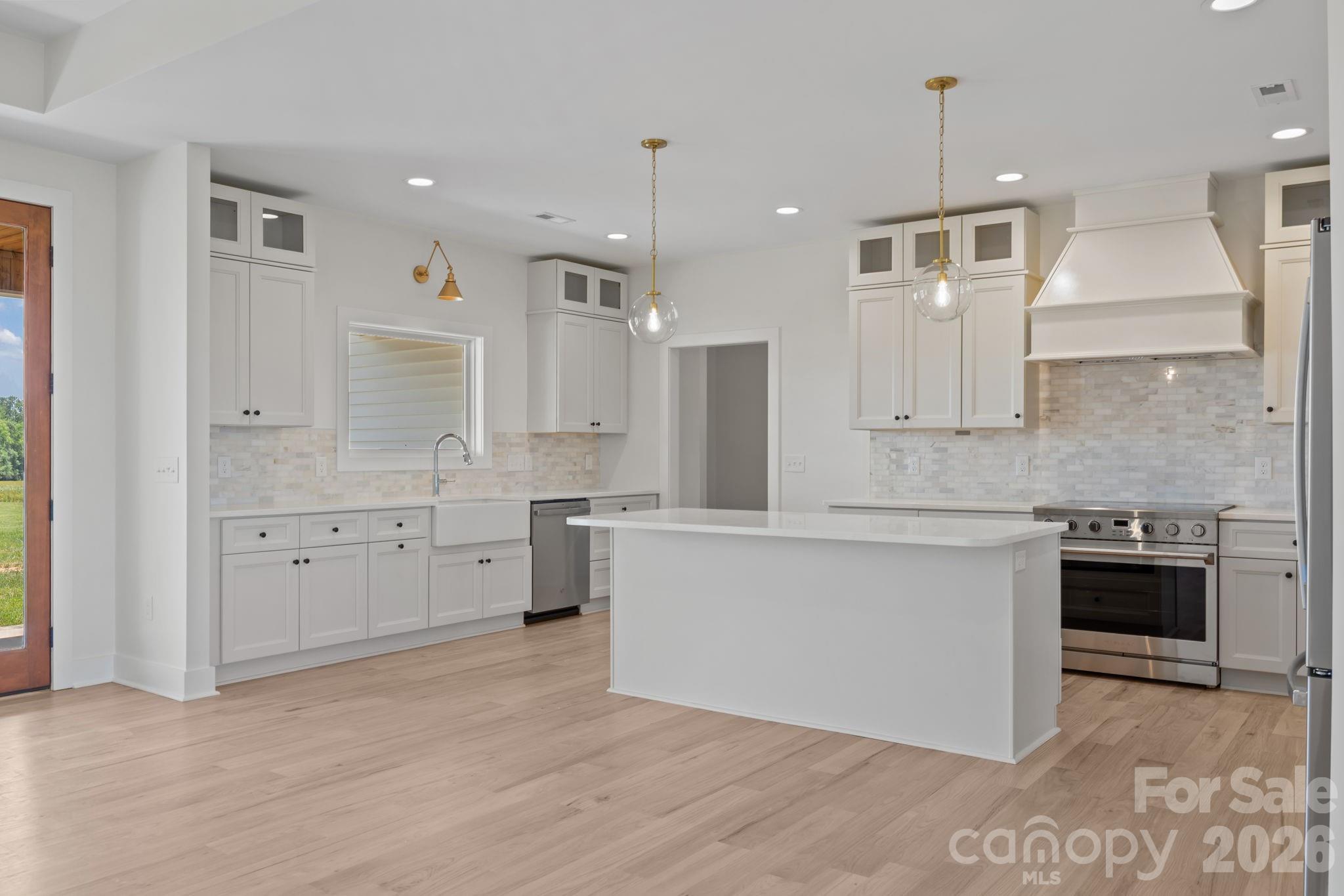 4805 Patterson Road China Grove, NC 28023 - Photo 14 of 42 a large white kitchen with granite countertop a stove a sink a refrigerator and white cabinets with wooden floor