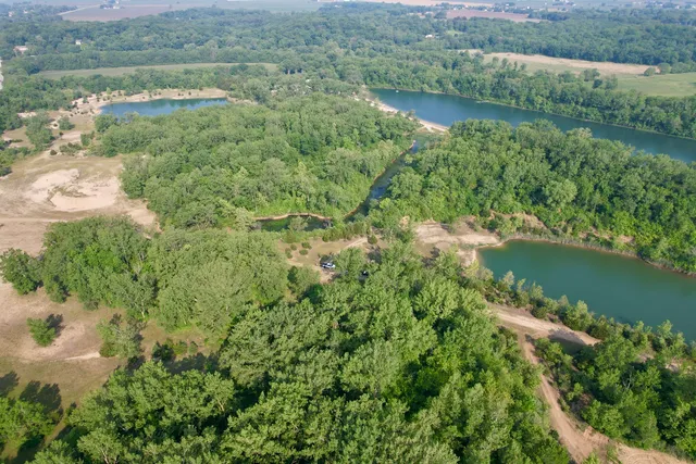 an aerial view of residential house with outdoor space and trees all around
