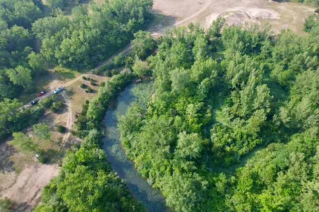 an aerial view of residential house with outdoor space and trees all around
