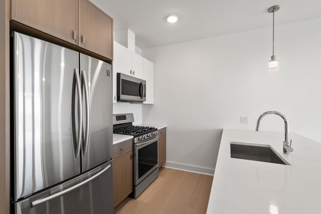 917 Bennington Street, Unit PH506 Boston, MA 02128 - Photo 4 of 11 a kitchen with stainless steel appliances a refrigerator sink and stove