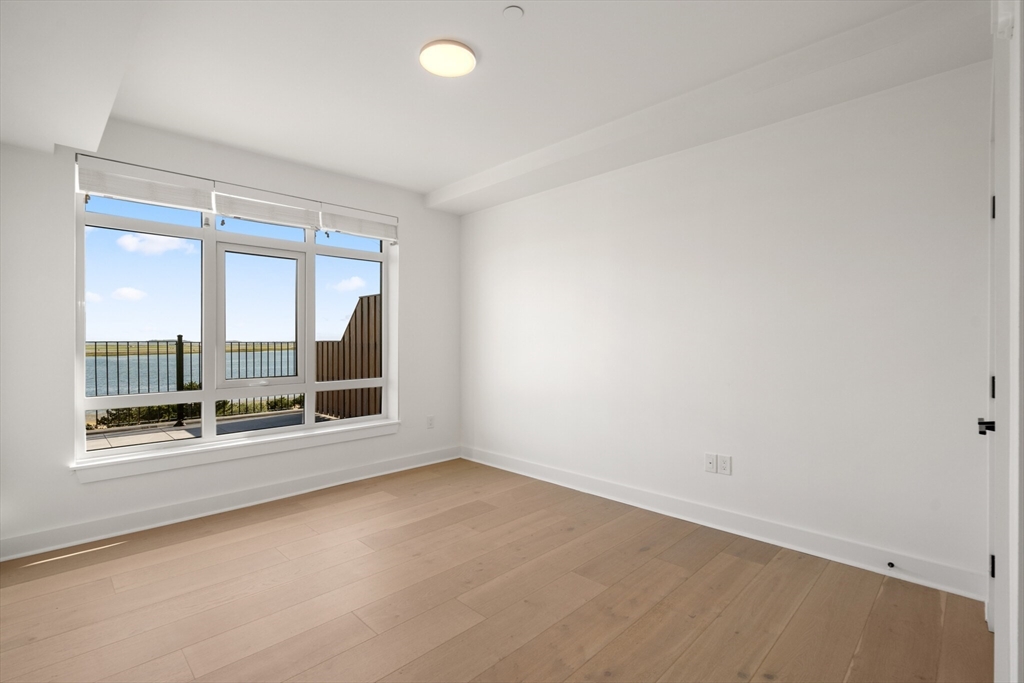 917 Bennington Street, Unit PH506 Boston, MA 02128 - Photo 6 of 11 an empty room with wooden floor and windows