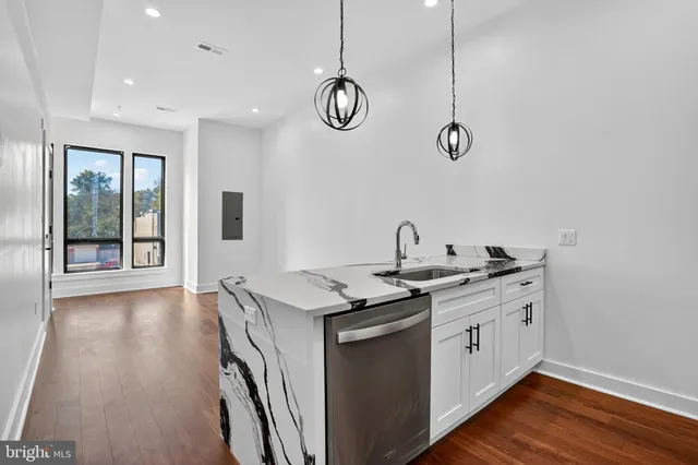 a kitchen with stainless steel appliances granite countertop a refrigerator a stove a sink dishwasher and a refrigerator with wooden floor