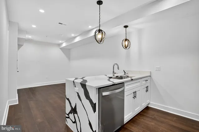 a kitchen that has a lot of cabinets a sink and a wooden floor