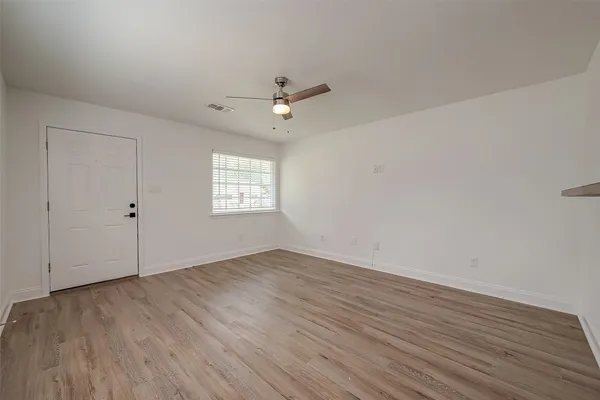 an empty room with wooden floor and windows