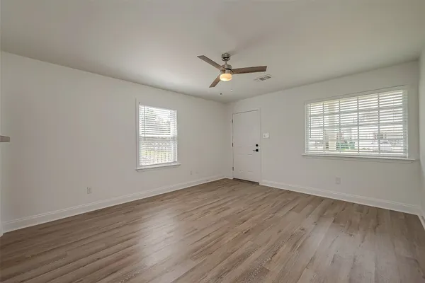 a view of an empty room with wooden floor and a window