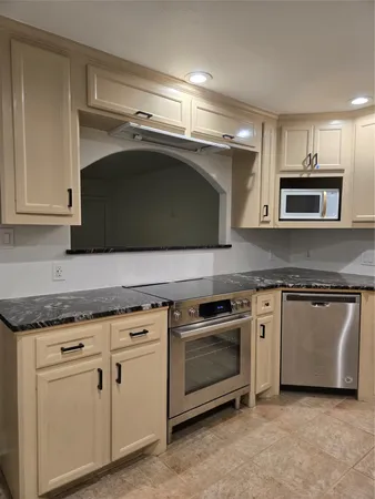a kitchen with granite countertop white cabinets and stainless steel appliances