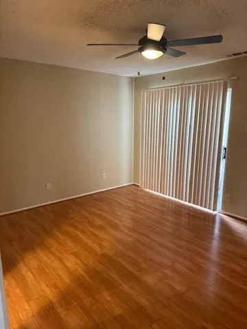 an empty room with wooden floor fan and windows