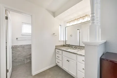 a bathroom with a granite countertop sink and a mirror