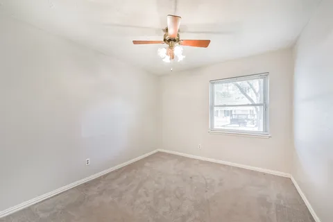 an empty room with a window and a ceiling fan