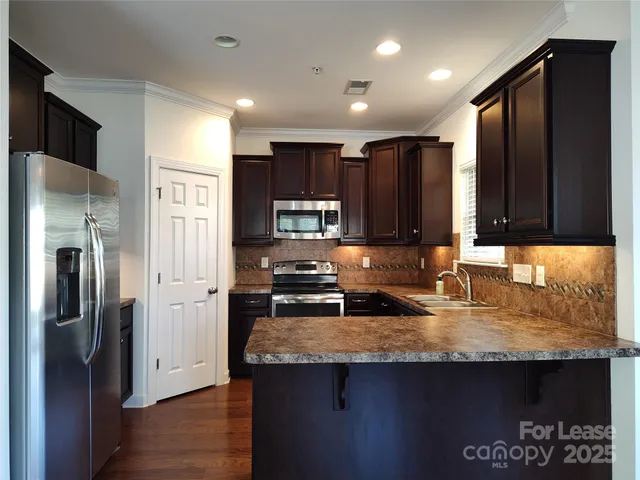 a kitchen with kitchen island granite countertop a refrigerator a stove and a sink