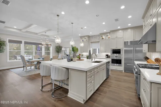 a large kitchen with kitchen island a sink a stove and a dining table with wooden floor
