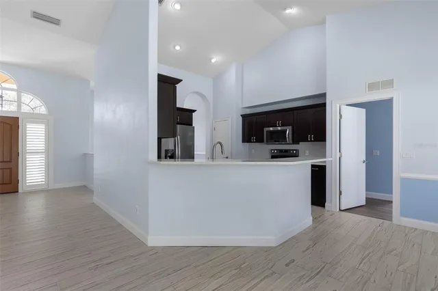 an empty room with wooden floor chandelier and windows