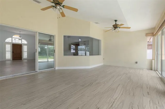 a view of an empty room with a window and wooden floor