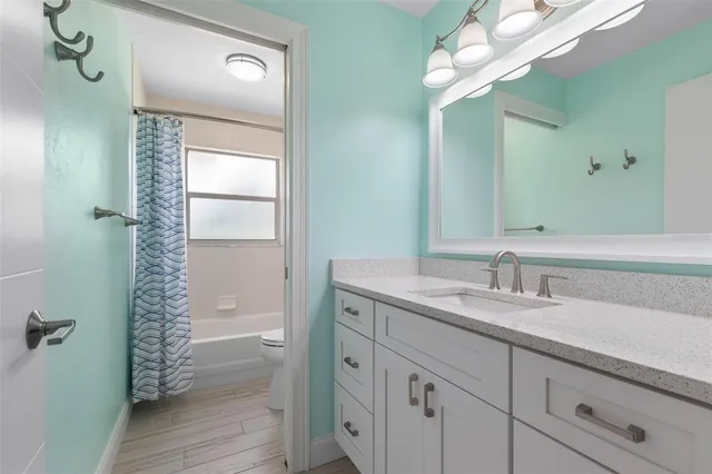 an empty room with wooden floor chandelier fan and windows