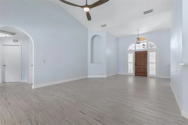 a view of an empty room with a window and wooden floor