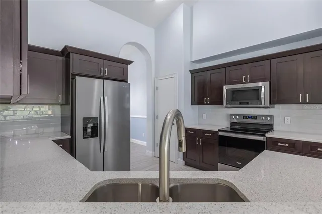a kitchen with stainless steel appliances kitchen island granite countertop a refrigerator and a sink