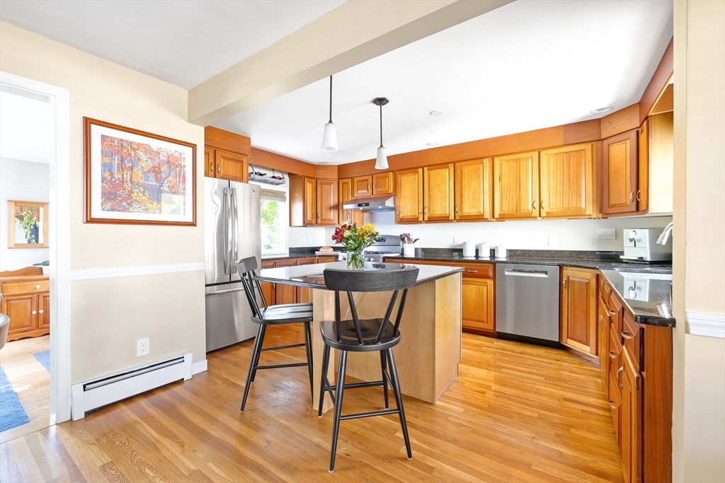 28 Cottage Street Natick, MA 01760 - Photo 5 of 32 a kitchen with stainless steel appliances granite countertop wooden floors and white cabinets