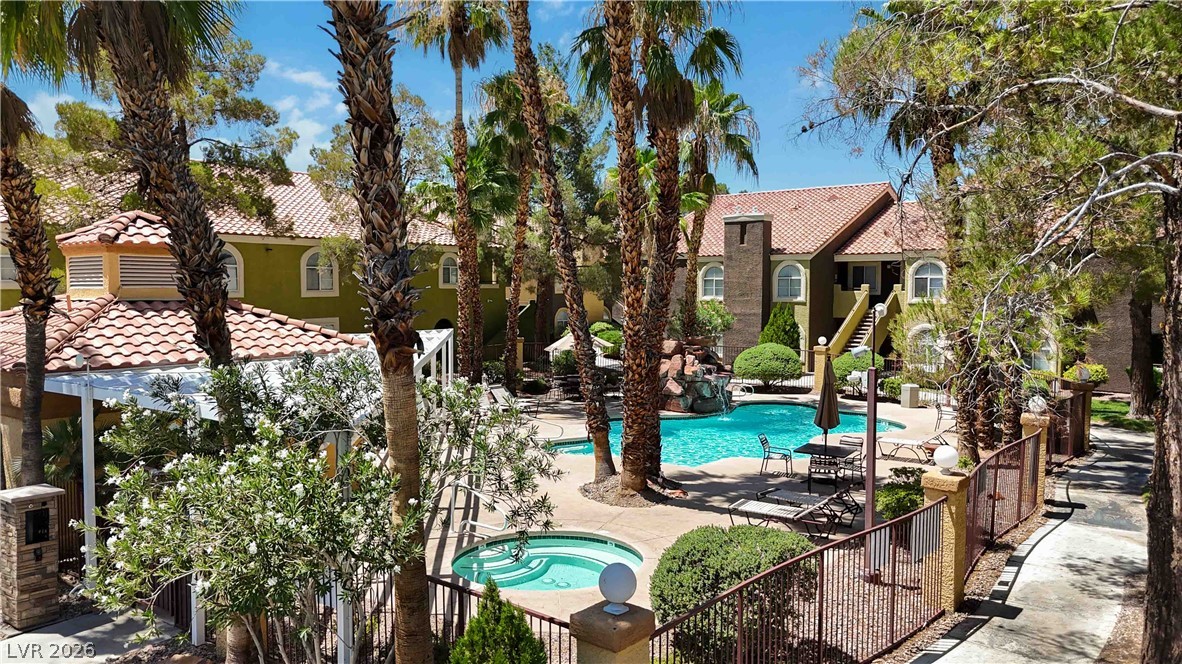 7950 West Flamingo Road, Unit 1180 Las Vegas, NV 89147 - Photo 2 of 26 A tranquil courtyard features a sparkling pool and spa, framed by lush landscaping and residential buildings.