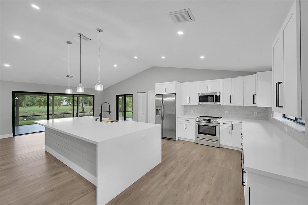 6195 Winding Brook Way Delray Beach, FL 33484 - Photo 14 of 68 a large kitchen with stainless steel appliances granite countertop a stove a sink a refrigerator and a wooden cabinets