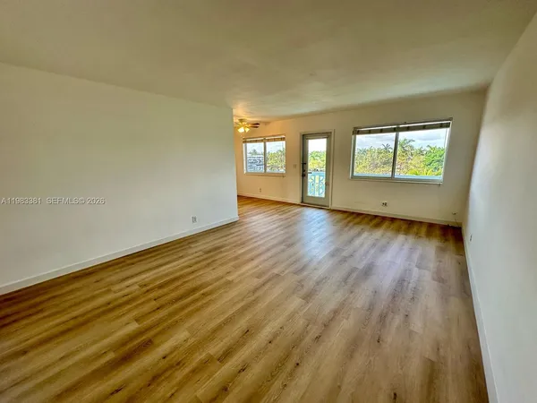 a view of an empty room with wooden floor and a window