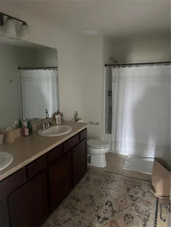 a bathroom with a sink a toilet a mirror and shower