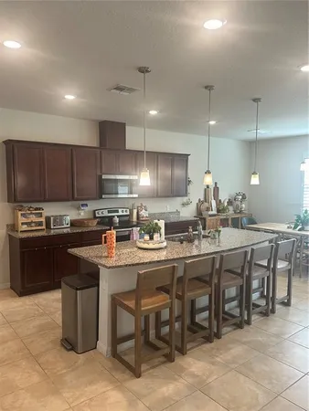 a kitchen with lots of wooden cabinets a sink table and chairs