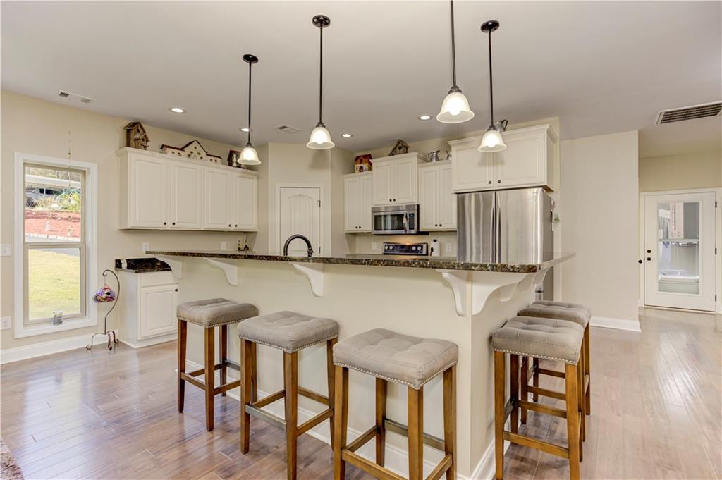 304 Garland Way Canton, GA 30115 - Photo 93 of 138 a kitchen with kitchen island granite countertop a table a stove a refrigerator and white cabinets with wooden floor