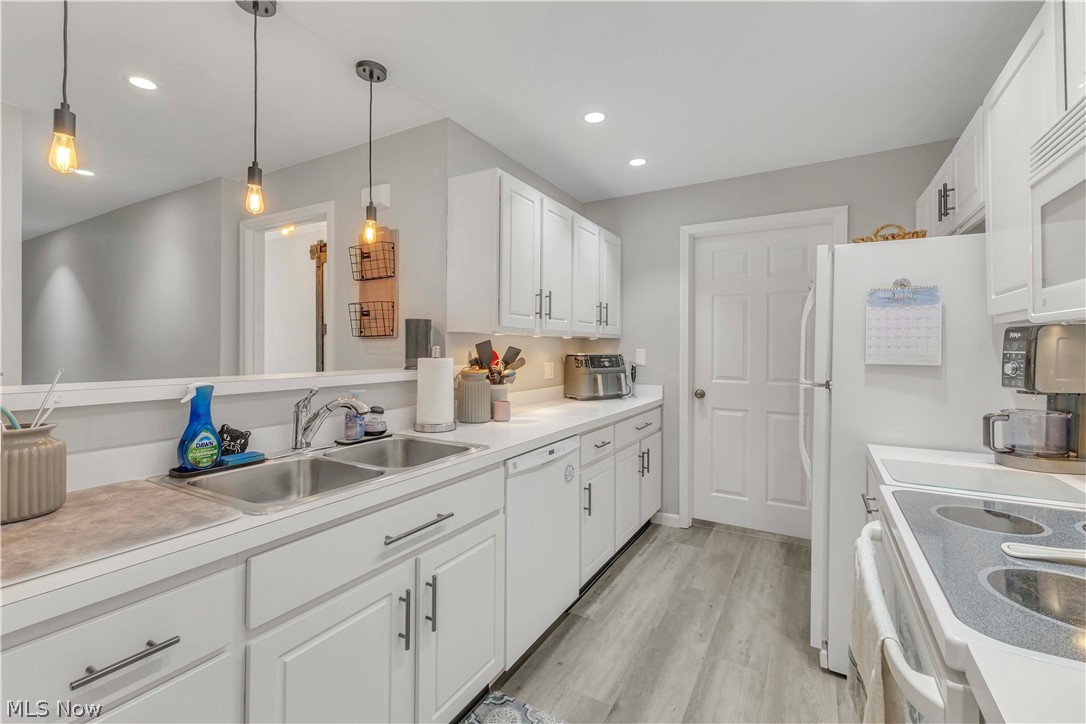 28340 Center Ridge Road, Unit 124 Westlake, OH 44145 - Photo 11 of 37 Kitchen featuring white cabinetry, light countertops, light wood finished floors, white appliances, and pendant lighting