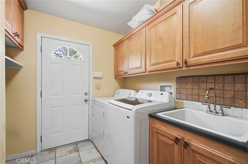 35780 Greer Road Murrieta, CA 92562 - Photo 37 of 56 Laundry room w plenty of cabinet storage, sink and doorway to exterior.