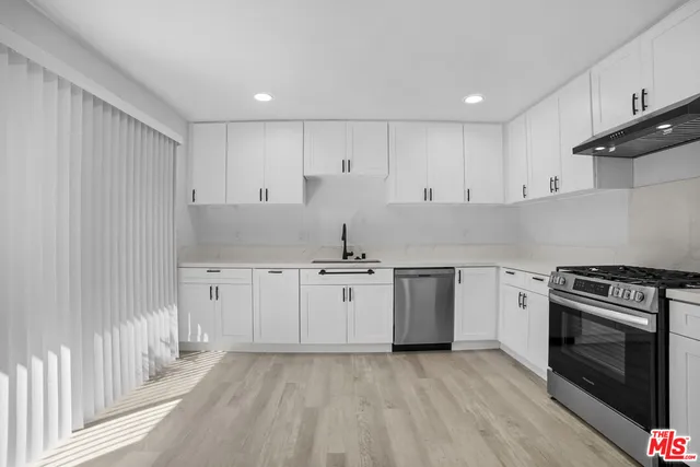 a kitchen with stainless steel appliances granite countertop a stove a sink and white cabinets