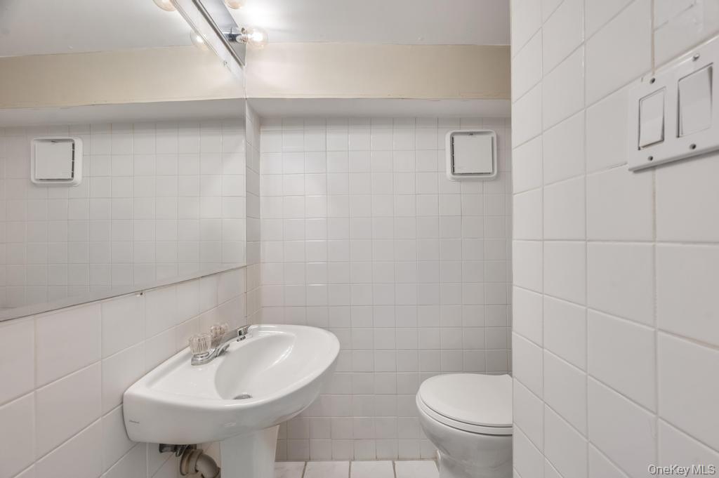 89-13 84th Street Queens, NY 11421 - Photo 27 of 34 Pedestal sink with chrome-finish faucet and wall-mounted mirror