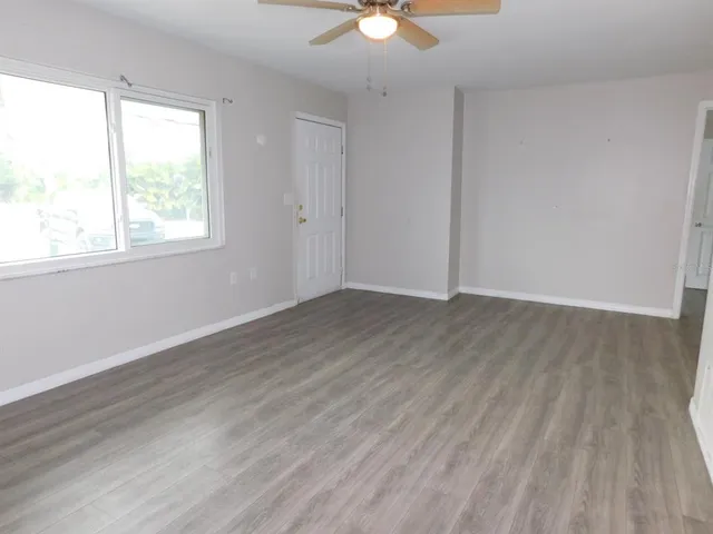 an empty room with wooden floor and windows