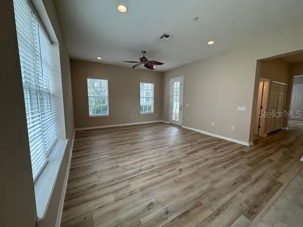 a view of an empty room with window and wooden floor