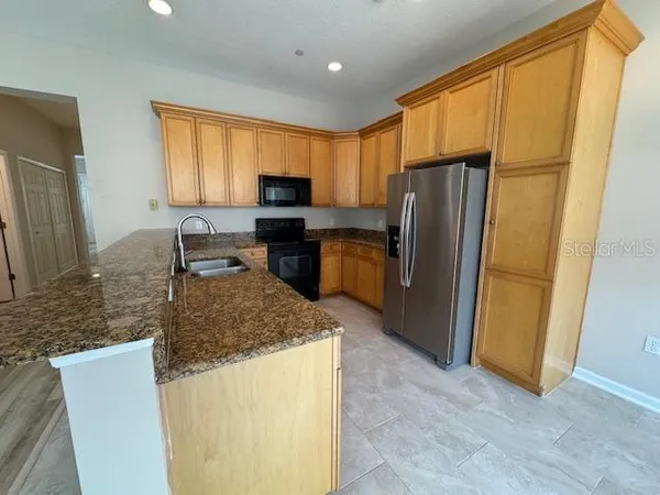 a kitchen with stainless steel appliances granite countertop a refrigerator a stove a sink a washer dryer and a refrigerator