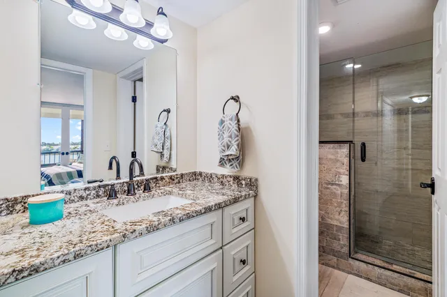 a bathroom with a granite countertop sink a mirror and shower
