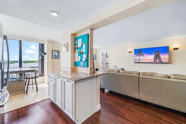 a living room with stainless steel appliances granite countertop furniture wooden floor and a large window