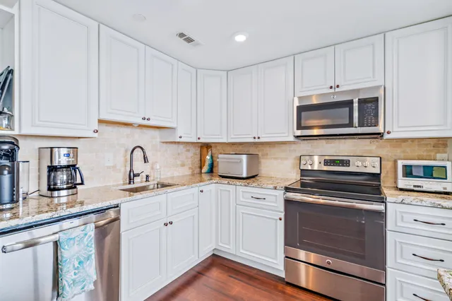a kitchen with granite countertop white cabinets and stainless steel appliances