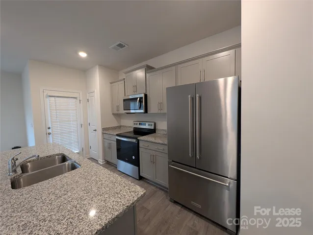 a kitchen with stainless steel appliances granite countertop a refrigerator a stove and a sink