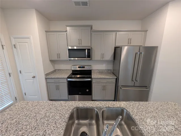 a kitchen with granite countertop a refrigerator and a stove top oven